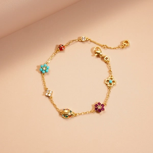 Detail of gold chain necklace with colorful enamel ladybug and zircon flower charms