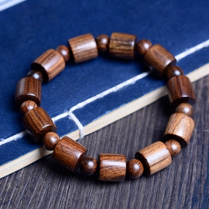Bracciale autentico con perle di legno e venature naturali su sfondo di libri vintage