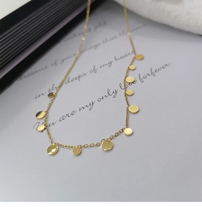 Macro detail of gold-plated titanium necklace with polished circular pendant charms