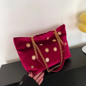 Magenta velvet tote bag with gold star studs and chain straps shown in a lifestyle setting
