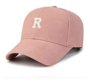 Close-up of the white embroidered letter R on a pink cotton baseball cap with fine stitching