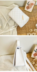 Detail of white quilted crossbody bag with diagonal flap and gold metal trim