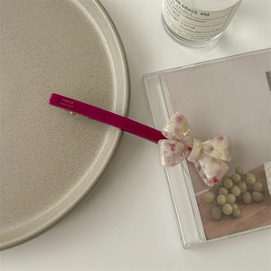 Close-up of acetate bow hair clip with colorful spots and FRANCE Handmade engraving