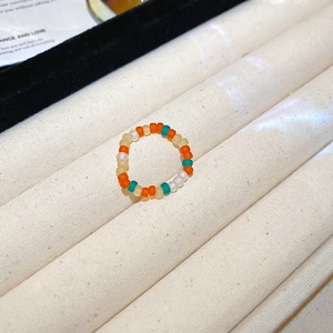 Detailed macro view of handmade colorful matte beaded rings on a beige velvet display stand