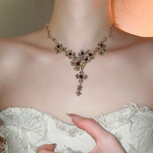 Close-up of vintage baroque gold flower necklace with red rhinestones on a female model