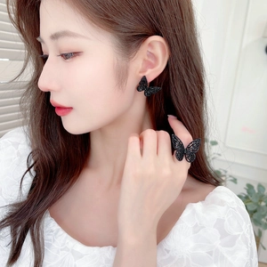 Close-up of black butterfly earring and adjustable ring set with shimmering details