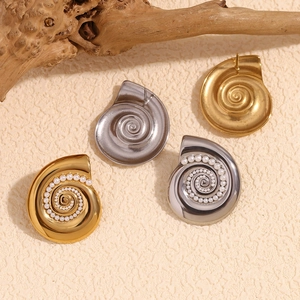 Macro detail of shell-shaped earrings with pearls in gold and silver finish
