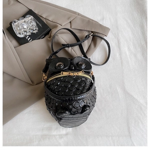 Detail of creative owl-shaped black PU leather bag with feather texture and gold zipper
