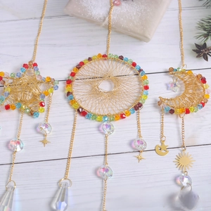 Detailed view of handmade crystal suncatchers with gold star, moon and round frames