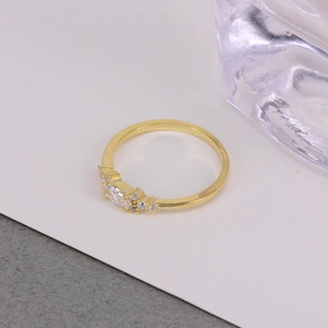 Close-up of a gold luxury ring featuring a claw setting with sparkling clear crystals