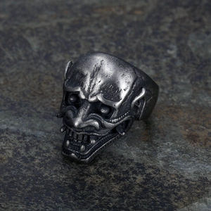 Macro shot of gothic skull ring with intricate silver-toned carvings on stone background