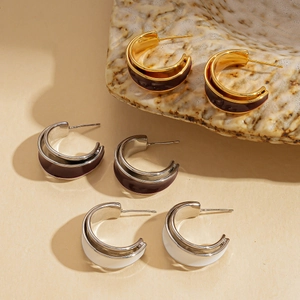 Close-up of three pairs of double-layer C-shape enamel hoop earrings in gold and silver