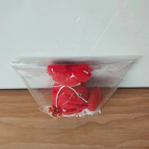 Detail of red plush gnome doll ornament with silver sequins and floral bead in packaging