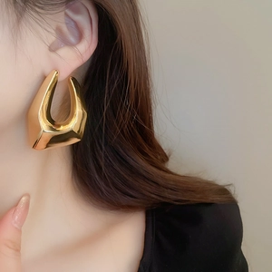 Gros plan sur les boucles d'oreilles géométriques dorées avec une finition métal poli