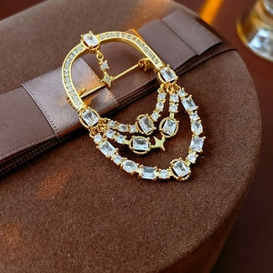 Détail d'une broche ovale plaquée or 18 carats avec glands en zircon sur boîte en velours