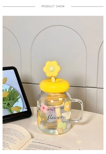 Detail of high-capacity glass cup with floral pattern, yellow flower lid and stirrer