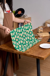 Macro detail of dark green Christmas napkin with gingerbread and tree prints on wooden table