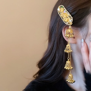 Detailed view of ethnic style golden hair clip with dangling bells and sparkling rhinestones