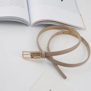 Detail of slim beige leather belt for women featuring gold buckle and white stitching