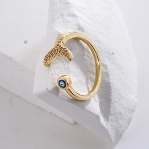 Detailed close-up of 18K gold-plated fish tail and evil eye charm on an open ring