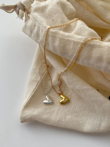 Gros plan de pendentifs cœur en argent 925 doré et argenté sur un petit sac en lin fin