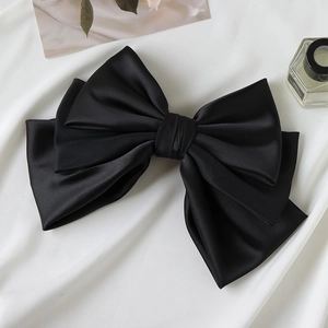 Detail of a large black satin multi-layer bow hair clip with elegant silk texture