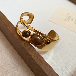 Detail of 18k gold plated stainless steel cuff bracelet with three brown tiger eye stones