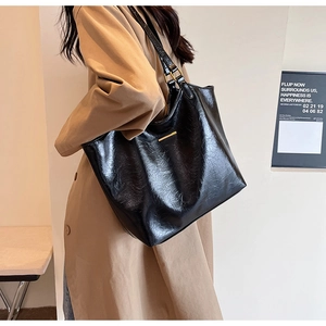 Detail of high-quality black faux leather tote bag featuring elegant gold metal accents