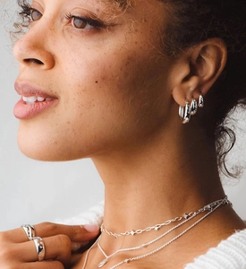 Close-up of model wearing silver star hoop earrings and layered necklaces set