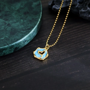 French style gold beaded necklace with blue enamel fishtail pendant on dark wood background