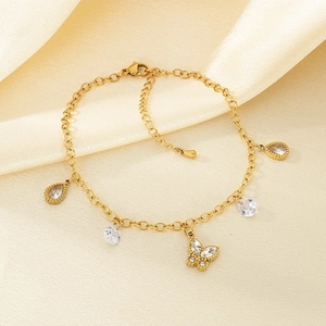 Detail of golden stainless steel anklet with crystal teardrops and butterfly charm