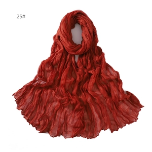 Detail of a deep red pleated scarf made of breathable chiffon with a soft crinkled texture