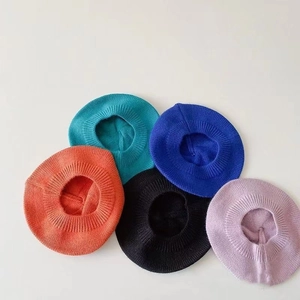 Détail à plat montrant une collection de cinq bérets tricotés colorés pour tout-petits