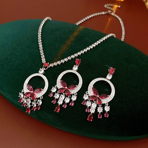 Detailed macro view of silver necklace and butterfly earrings with red zircon teardrops