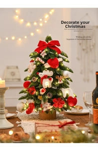Mini tabletop Christmas tree with warm LED lights and festive ornaments on wooden base