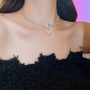Detail showing a gold-plated necklace with a teardrop zircon and an elegant white pearl