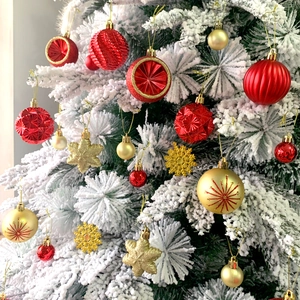 Close-up of red and gold Christmas ball ornaments and snowflakes on a white tree