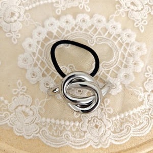 Detailed close-up of a black elastic hair tie featuring an interlocking silver metal ring