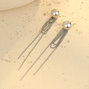 Close-up of silver stainless steel earrings with ball studs and dangling chain tassels