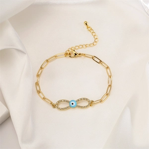 Detail of infinity charm with devil eye on golden chain over white silk fabric