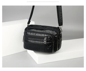 Détail du sac bandoulière noir en similicuir crocodile avec plusieurs compartiments zippés