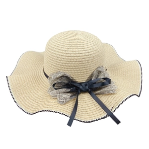 Beige wide brim straw sun hat with black ribbon bow and decorative wavy stitched edge