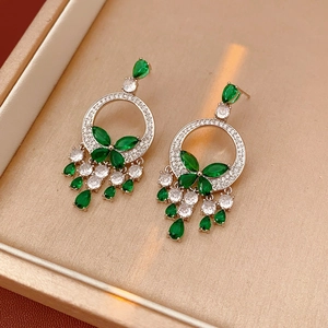 Détail de boucles d'oreilles papillon émeraude et collier dans un écrin à bijoux beige