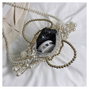 Detail of beaded pearl evening bag with gold frame and drawstring lining holding essentials