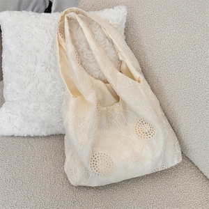 Close-up of intricate floral lace embroidery and hollow patterns on beige canvas tote bag