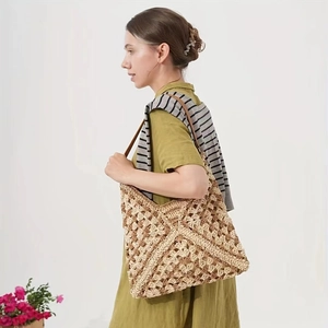 Dettaglio borsa in paglia intrecciata kaki con tracolla marrone mostrata su una modella