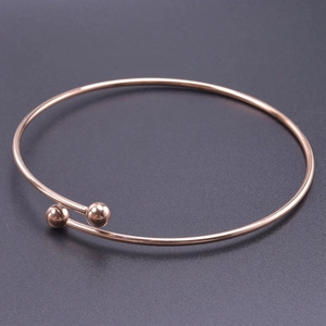 Detail of rose gold stainless steel open bangle with dual polished spheres design
