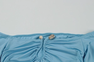Close-up of light blue dress with keyhole neckline and marble beads detail