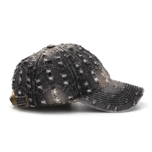 Side view detail of a vintage distressed washed denim baseball cap with ripped design.
