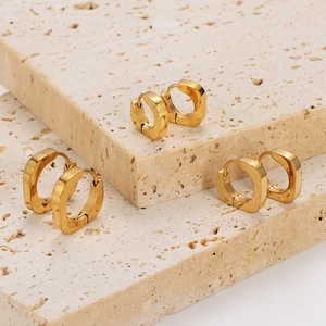Polished gold square hoop earrings displayed on minimalist beige stone steps